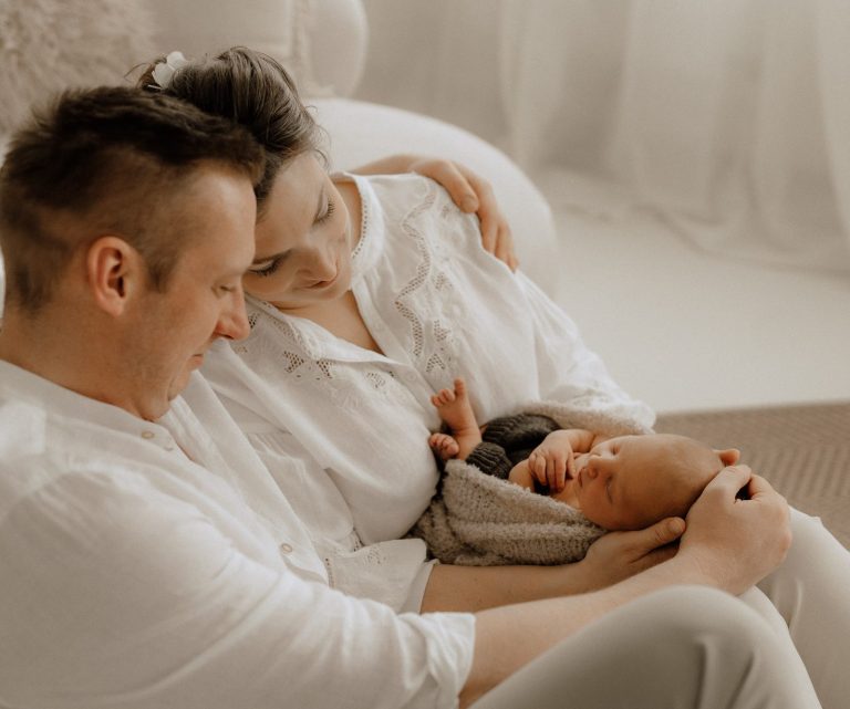 Eltern halten liebevoll ihr schlafendes Baby in einer ruhigen, hellen Umgebung.
