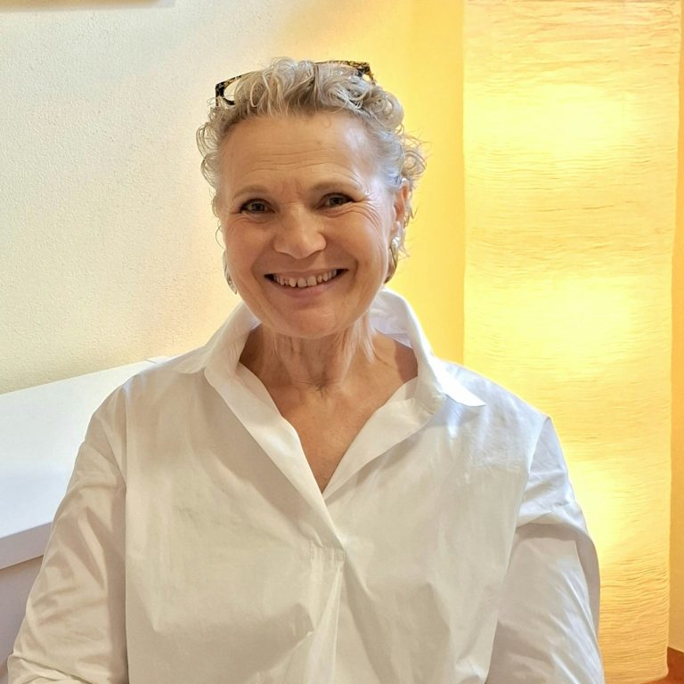 Sabine Erber, sitzt in ihrer Praxis "Aufwerts" mit Dekoration im Hintergrund.